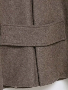 Macro shot of dark brown wool coat showing fine twill texture and neat stitching details