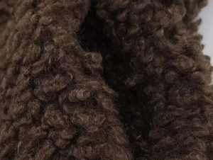 Close-up of deep brown thick teddy fleece fabric showing curly wool texture for winter jackets