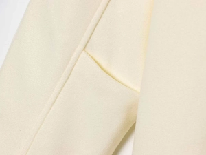 Detailed macro view of the neat stitching and soft beige wool texture on the coat pocket