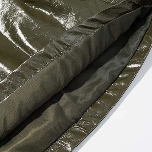 Detail of glossy dark olive leather fabric with smooth texture and layered stitching