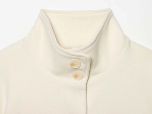 Detail of cream cape coat collar with stylish marbled buttons and premium wool texture