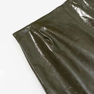 Close-up of olive green glossy faux leather fabric showing reflective texture and folds