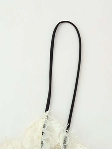 Close-up of white floral lace top with eyelash trim and contrasting black thin strap