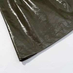 Detail of dark olive green faux leather fabric with glossy finish and double-stitched hem