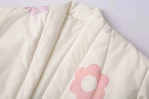 Dettaglio ravvicinato dello scollo della giacca trapuntata con fiori rosa