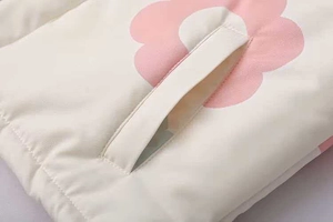 Dettaglio del piumino crema con stampa floreale rosa e design della tasca trapuntata