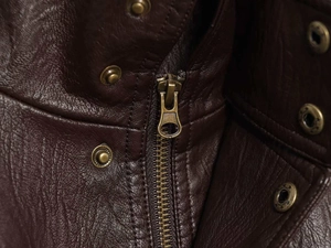 Detail of dark brown leather jacket featuring lychee texture and bronze metal zipper