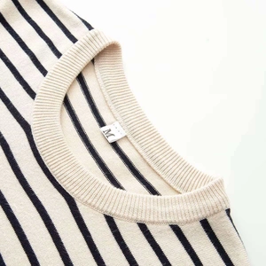 Close-up of the round neckline and striped knit texture of the cream and black cardigan
