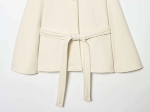 Detail of waist belt and button on cream white wool cape coat with elegant soft texture