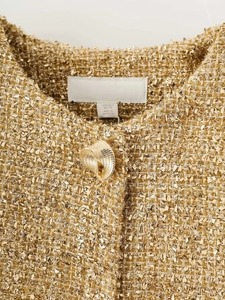 Detailed close-up of metallic golden tweed jacket collar with textured gold button detail