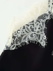 Detailed macro view of black chiffon top featuring delicate white eyelash floral lace trim