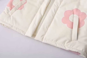 Dettaglio del gilet imbottito con stampa floreale, cerniera e tasche laterali