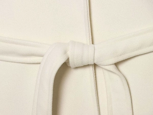 Detail of the soft wool fabric texture and tie-waist belt on a beige cloak coat