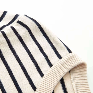 Detailed close-up of beige knit cardigan fabric with horizontal black stripes and texture