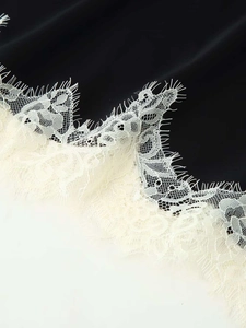 Close-up of delicate white eyelash lace trim stitched on a premium black camisole top