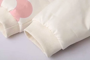 Dettaglio del polsino a coste della giacca bianco crema con stampa di nuvole rosa