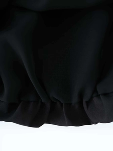 Close-up of the black chiffon fabric showing detailed smocked cuffs and pleated texture