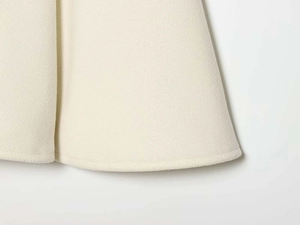 Macro detail of beige wool coat hem showing fine felt texture and rolled edge stitching