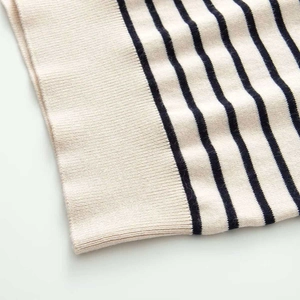 Detail of navy blue stripes on cream knitted cardigan with ribbed cuff texture