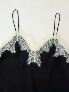 Close-up of delicate cream eyelash lace trim on black silk camisole top with thin straps
