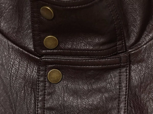 Detail view of dark brown leather jacket with vintage bronze buttons and neat stitching