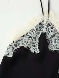 Detailed close-up of white eyelash lace trim on black camisole top with thin straps