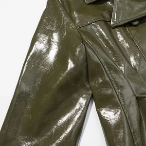 Close-up of olive green patent leather jacket showing shiny texture and shoulder seam