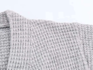 Gros plan sur la texture en maille gris clair et les coutures de l'épaule et du col