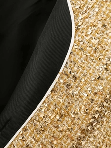 Detail of golden tweed jacket with sequins, black lining and white contrast piping
