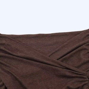 Détail du tissu en maille marron foncé avec pli croisé et texture finement tissée