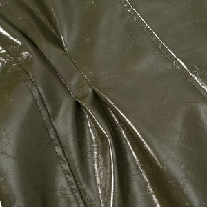 Macro detail of dark olive faux leather with glossy finish and fine double stitching