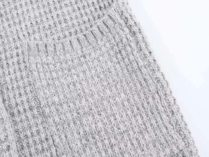 Gros plan détaillé sur la maille gris clair avec motif gaufré et bordure côtelée