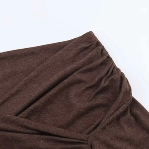 Détail du tissu en maille marron foncé avec plis élégants et design croisé chic