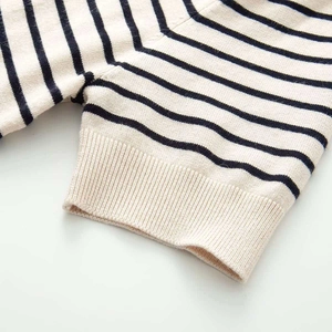 Detailed macro view of navy blue and cream striped knit top with ribbed cuff texture