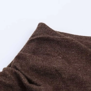 Gros plan sur la texture du tricot fin marron et le détail de l'ourlet côtelé pour ce haut