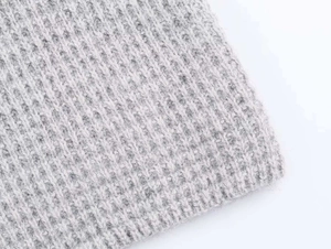 Gros plan sur la texture maille côtelée gris clair d'un cardigan long pour femme