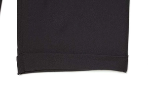 Détail de l'ourlet de pantalon noir montrant la texture du tissu sergé de qualité