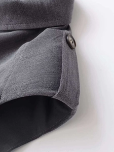 Detail shot of grey twill fabric texture with dark button and neat stitching on dress