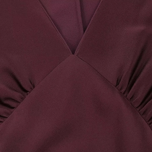 Vue détaillée d'une robe bordeaux satinée avec col en V et drapé plissé sophistiqué