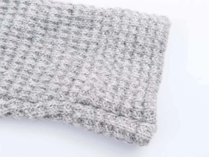 Détail en gros plan de la maille épaisse gris clair sur le long cardigan
