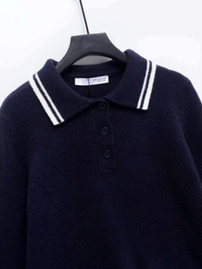 Detail view of navy knit polo shirt collar with white stripes and branded size label