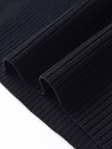 Close-up of black ribbed knit fabric showing detailed vertical texture and premium stitching