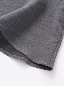 Detailed view of dark grey woven fabric with diagonal twill texture and neat stitched hem