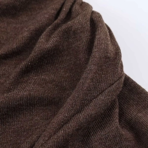 Gros plan sur la maille fine marron foncé montrant la texture douce et les plis