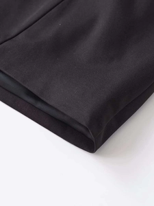 Gros plan sur la texture du tissu en sergé noir et les détails de l'ourlet du combishort