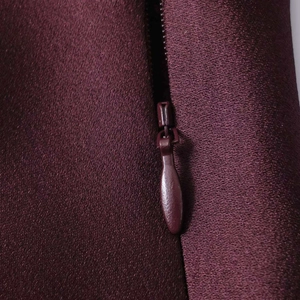 Gros plan d'une robe en satin bordeaux montrant une fermeture éclair invisible et du tissu