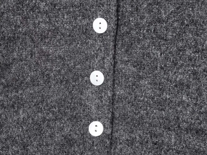Close-up of grey knit cardigan featuring thick wool texture and three white round buttons