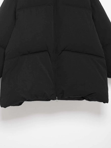Detailed macro view of black puffer jacket showing metal zipper and large side pockets