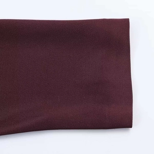 Gros plan détaillé montrant la texture satinée et le tissu violet foncé de la robe