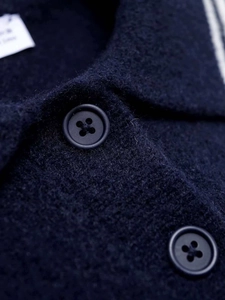 Macro shot of dark blue knit fabric texture and premium black round buttons with cross stitching